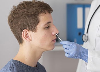врач берёт мазок из носа пациента